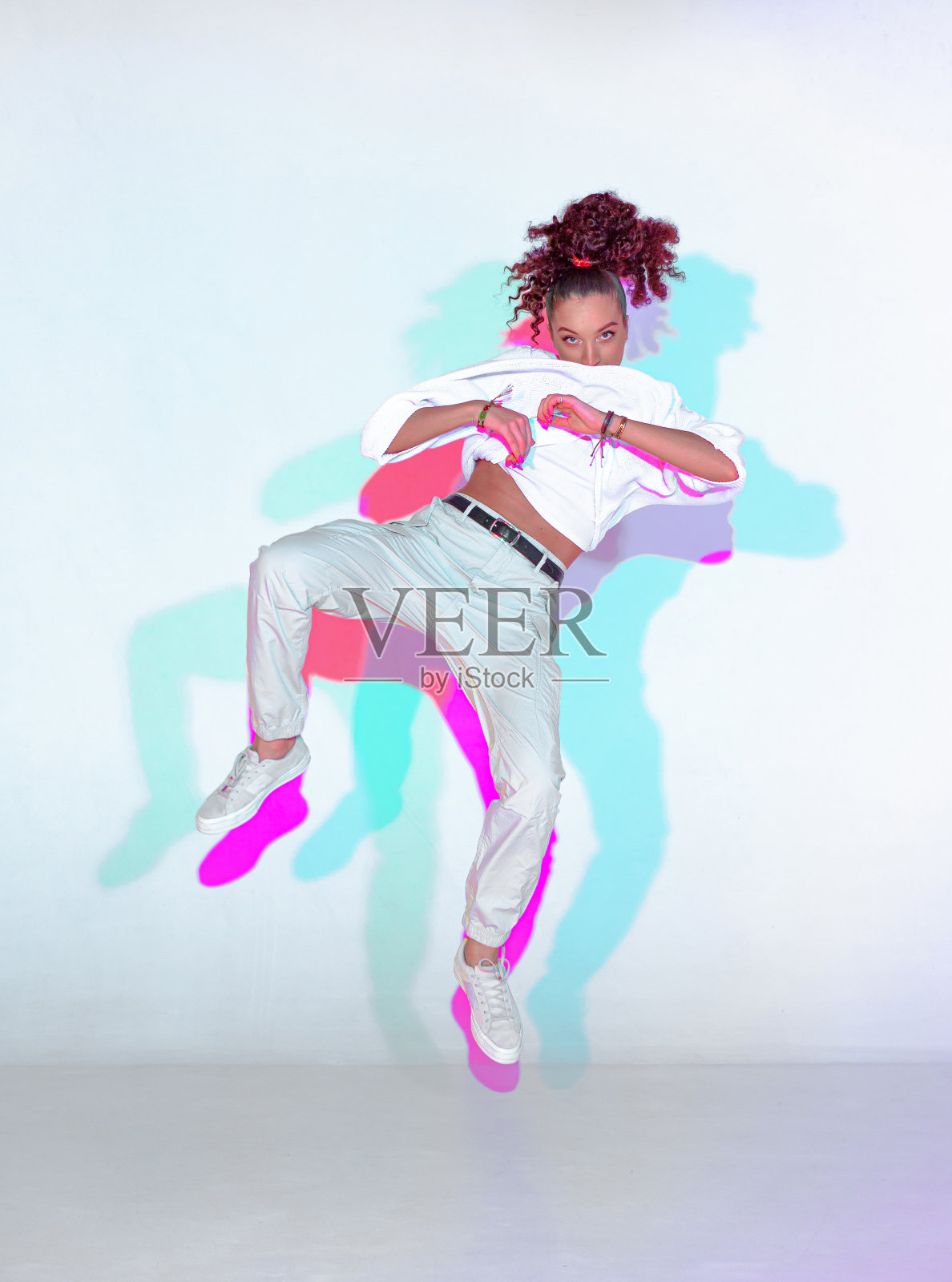 跳舞的混血年轻女孩在彩色霓虹灯演播室。跳街舞的女舞者照片摄影图片