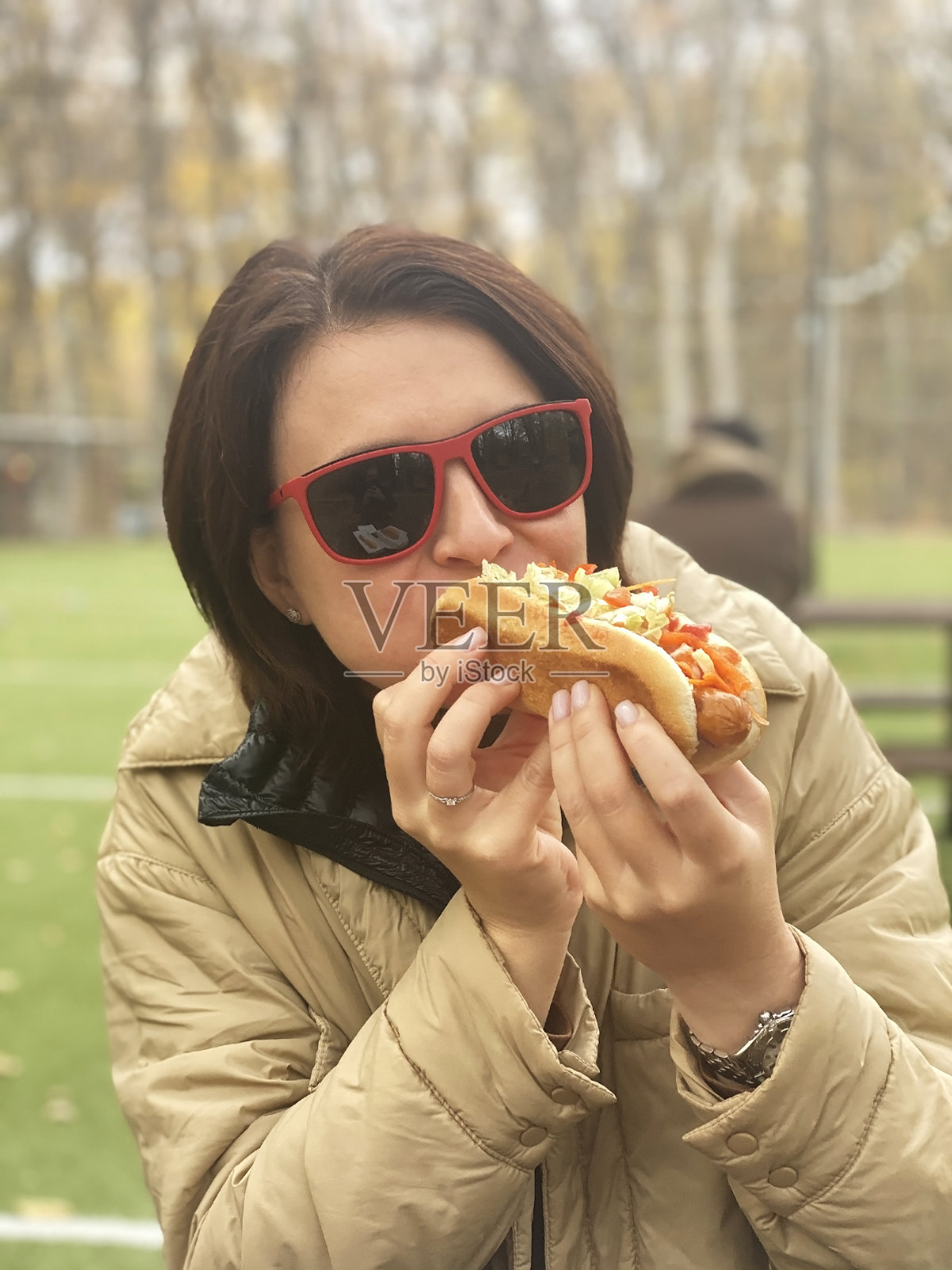 一个年轻女子坐在街上的咖啡馆里吃着热狗照片摄影图片
