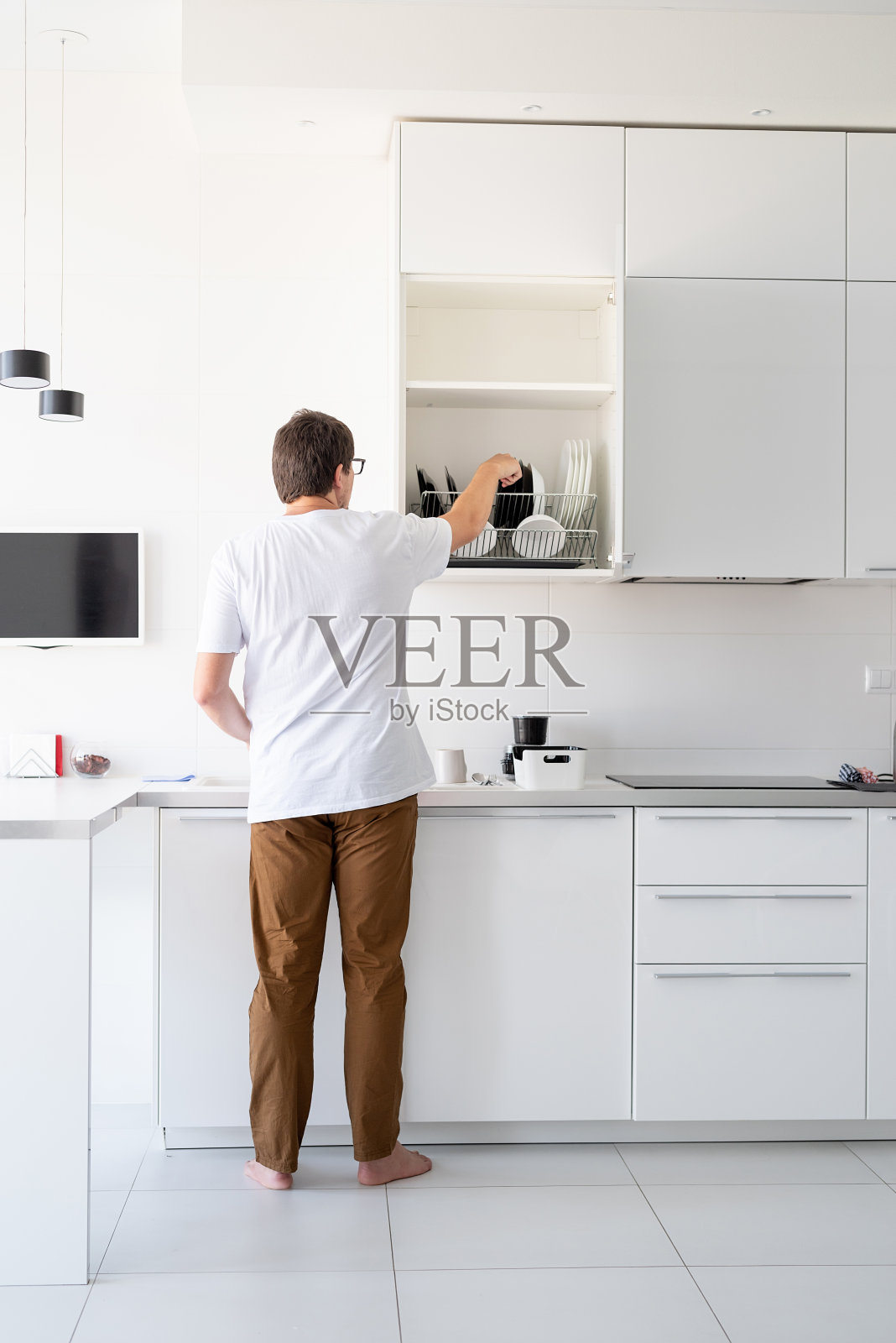 穿着白色t恤的男人在厨房洗盘子照片摄影图片