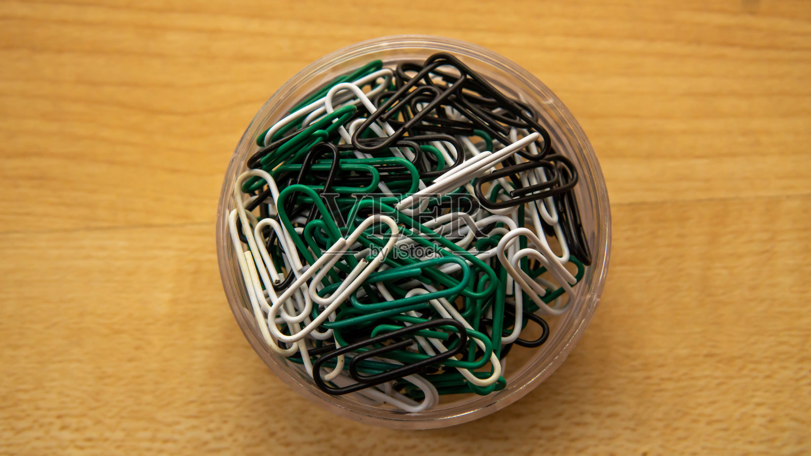 全回形针在一个透明的盒子在木制背景的俯视图。照片摄影图片