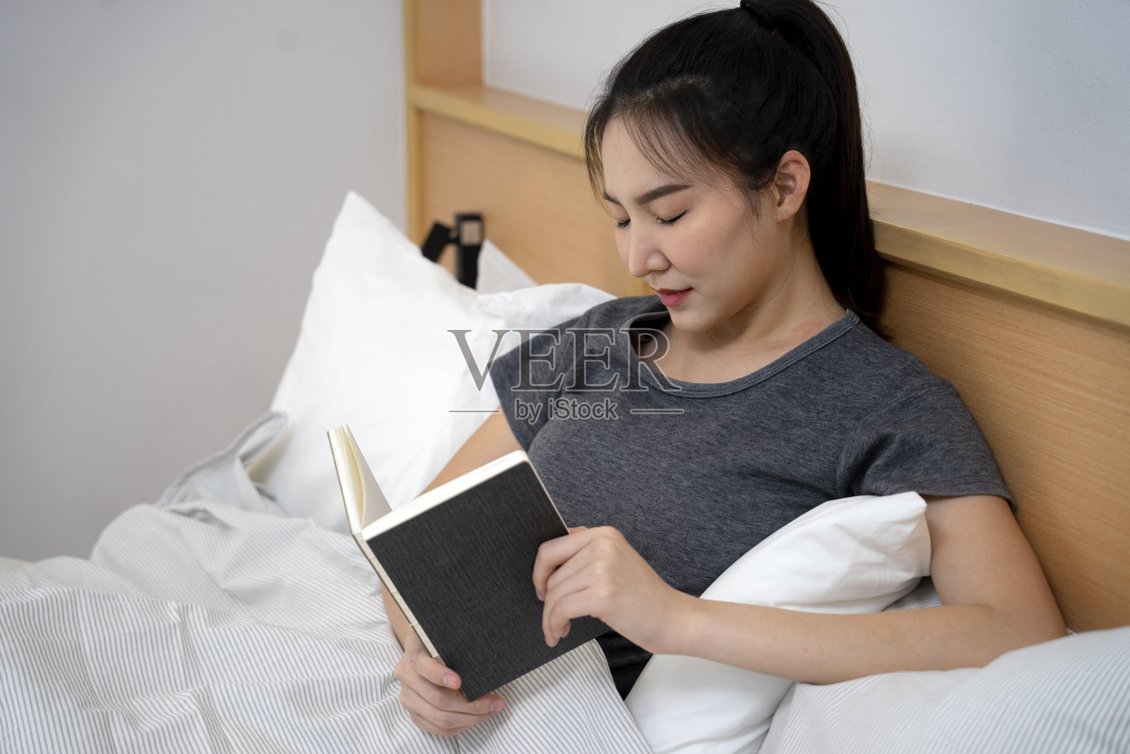 年轻的亚洲美女闭上眼睛睡觉，她读照片摄影图片