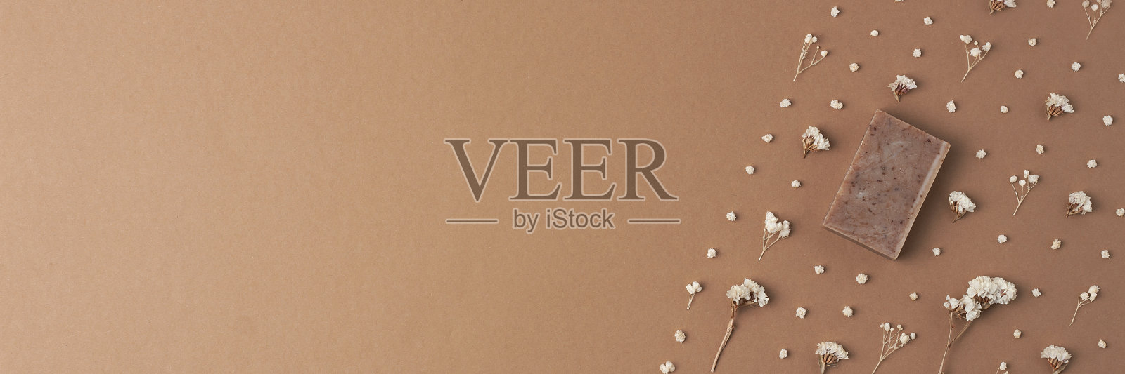 棕色背景上的肥皂和花。平铺，复制空间。照片摄影图片