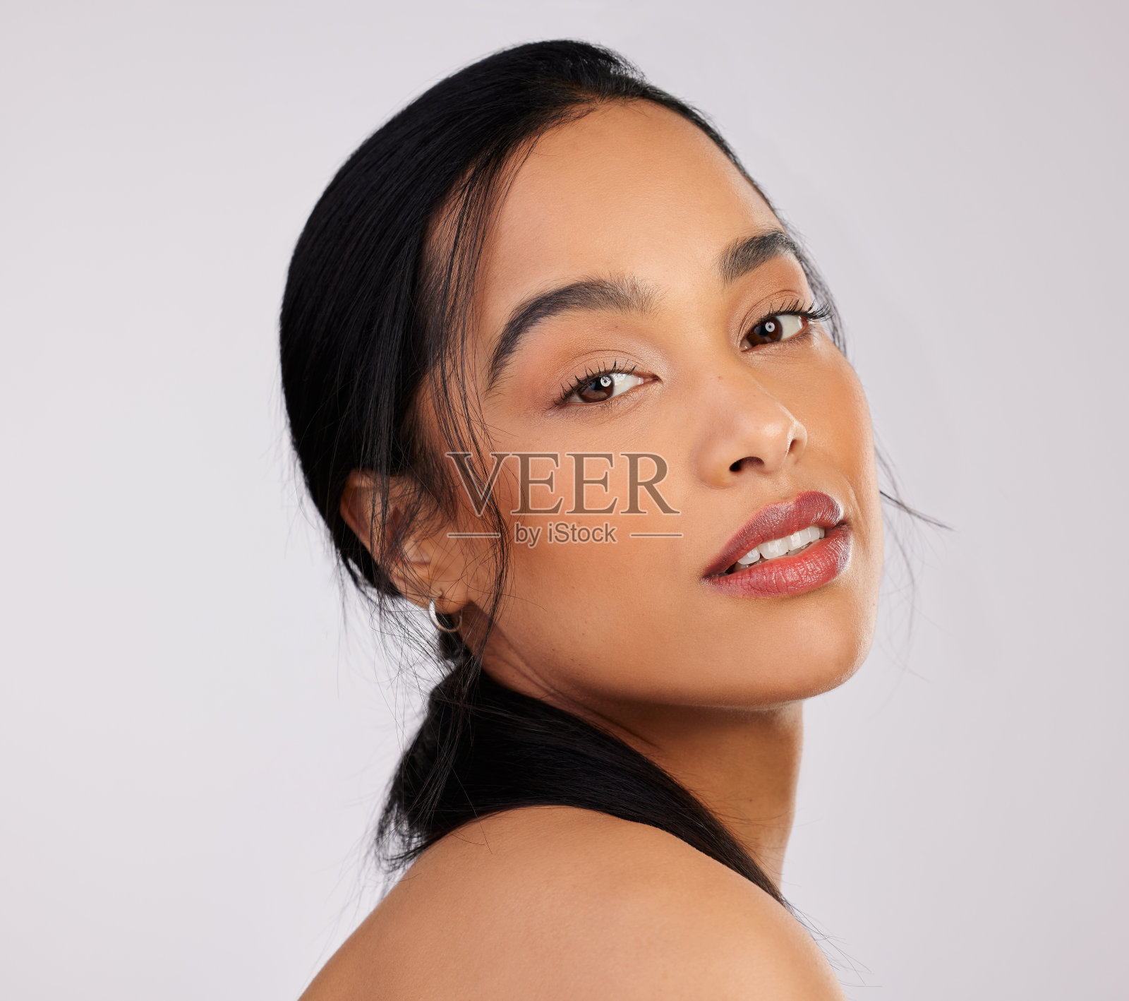 摄影棚拍摄了一个美丽的年轻女子在灰色的背景下摆姿势照片摄影图片