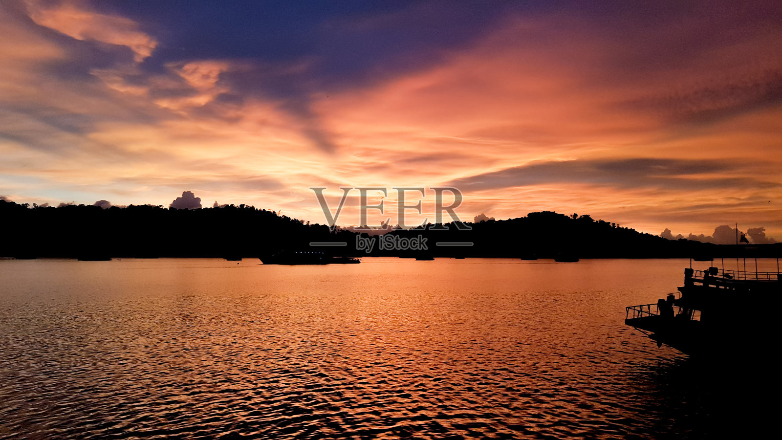 夕阳中的塔布卢姆码头上的轮船轮廓。照片摄影图片