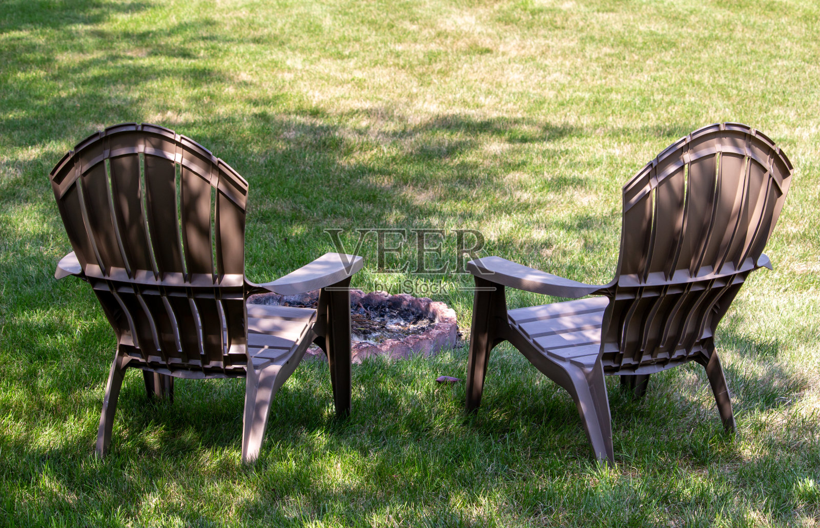 在一个熄灭的火坑周围，一对草坪椅子在一个浅色的阴影照片摄影图片