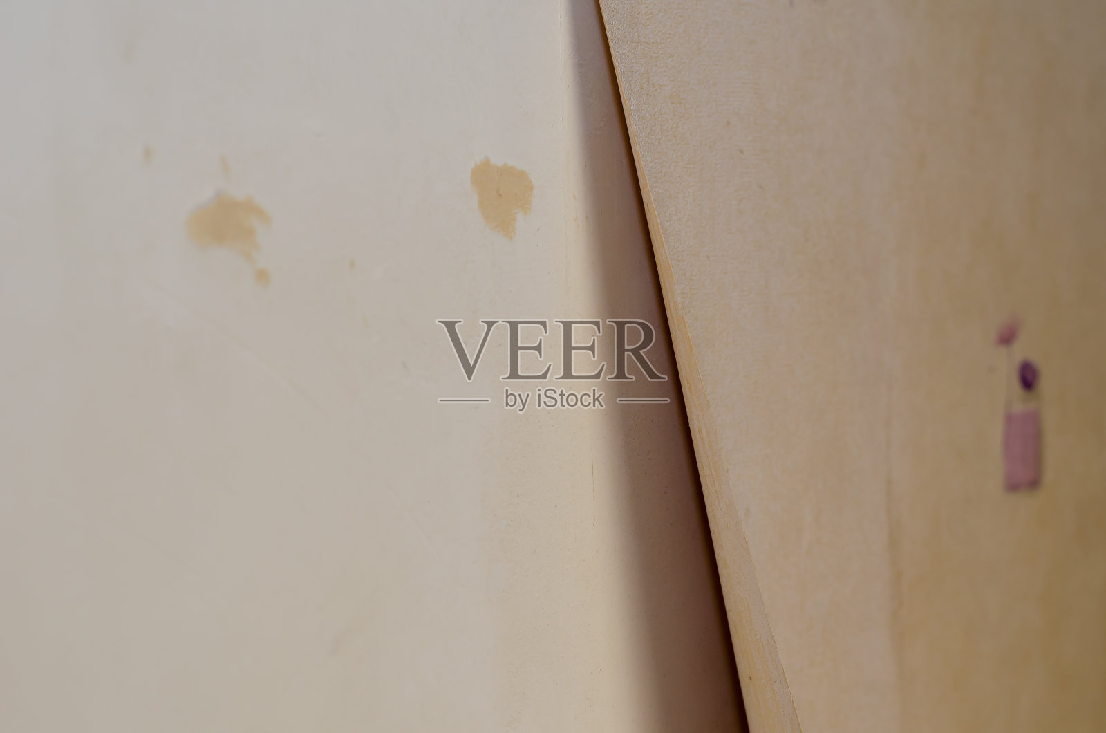 乙烯基墙纸正在从墙上剥落。米色墙纸是剥皮的照片摄影图片