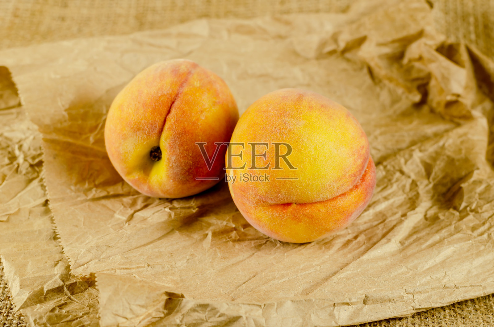 牛皮纸上的熟桃子。两个红色的水果。午餐袋。特写镜头照片摄影图片