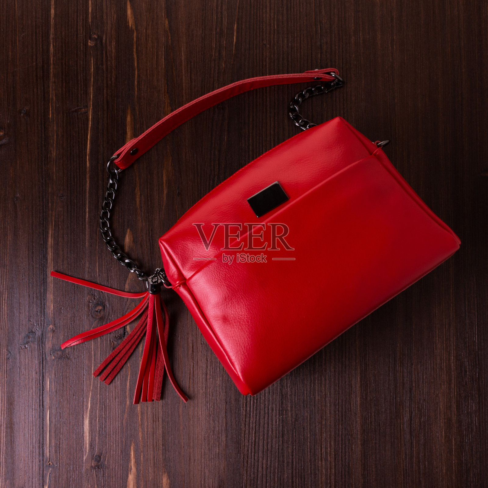 红色皮革包为妇女在一个棕色木材纹理的背景。照片摄影图片
