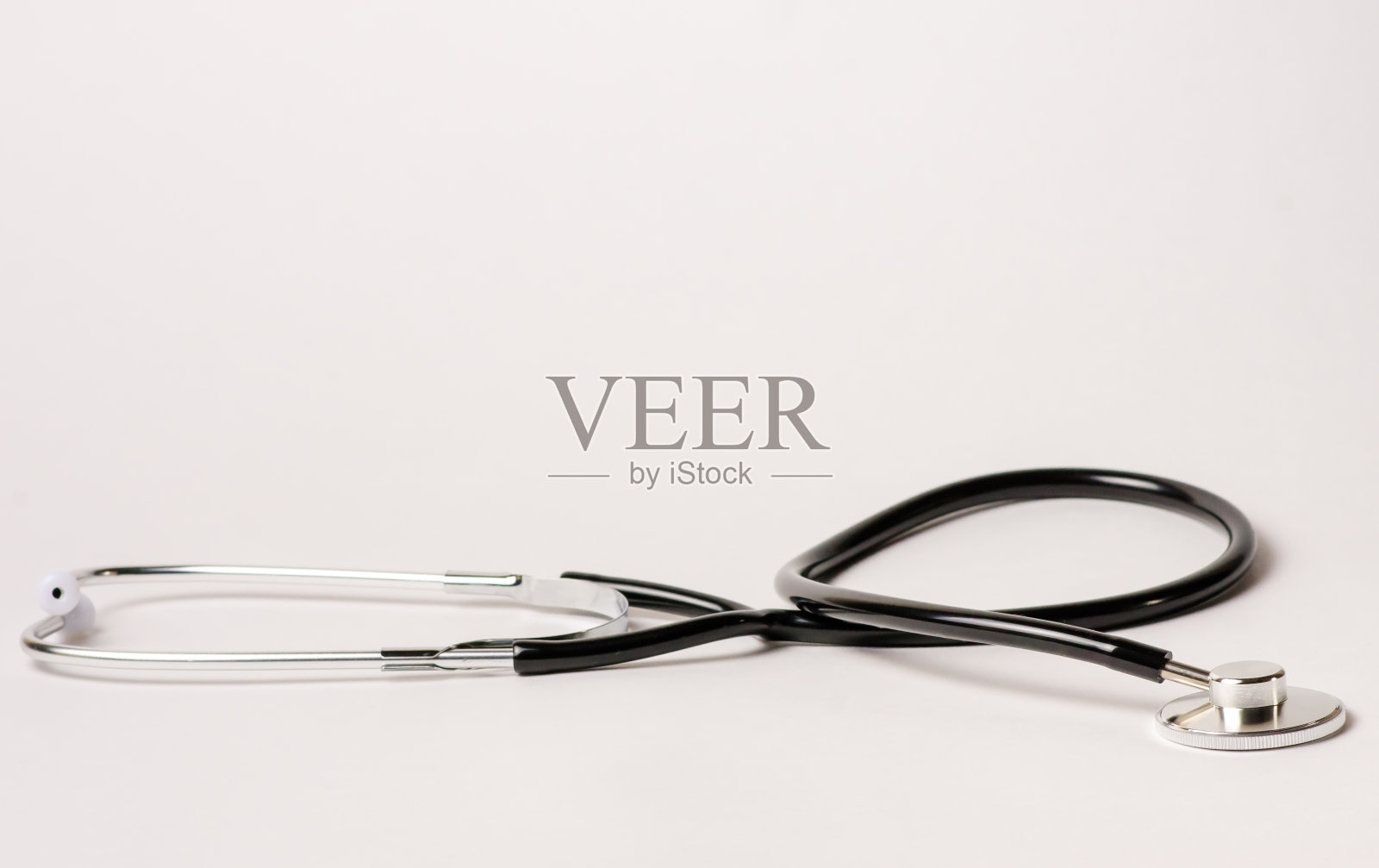 在医生办公室的桌子上，白色背景上放着一个听诊器，用来听心跳，复制空间，平躺照片摄影图片