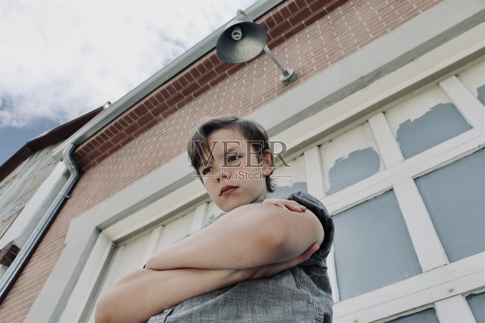 青春期男孩独自站在大楼前，看起来心烦意乱或生气-库存照片照片摄影图片