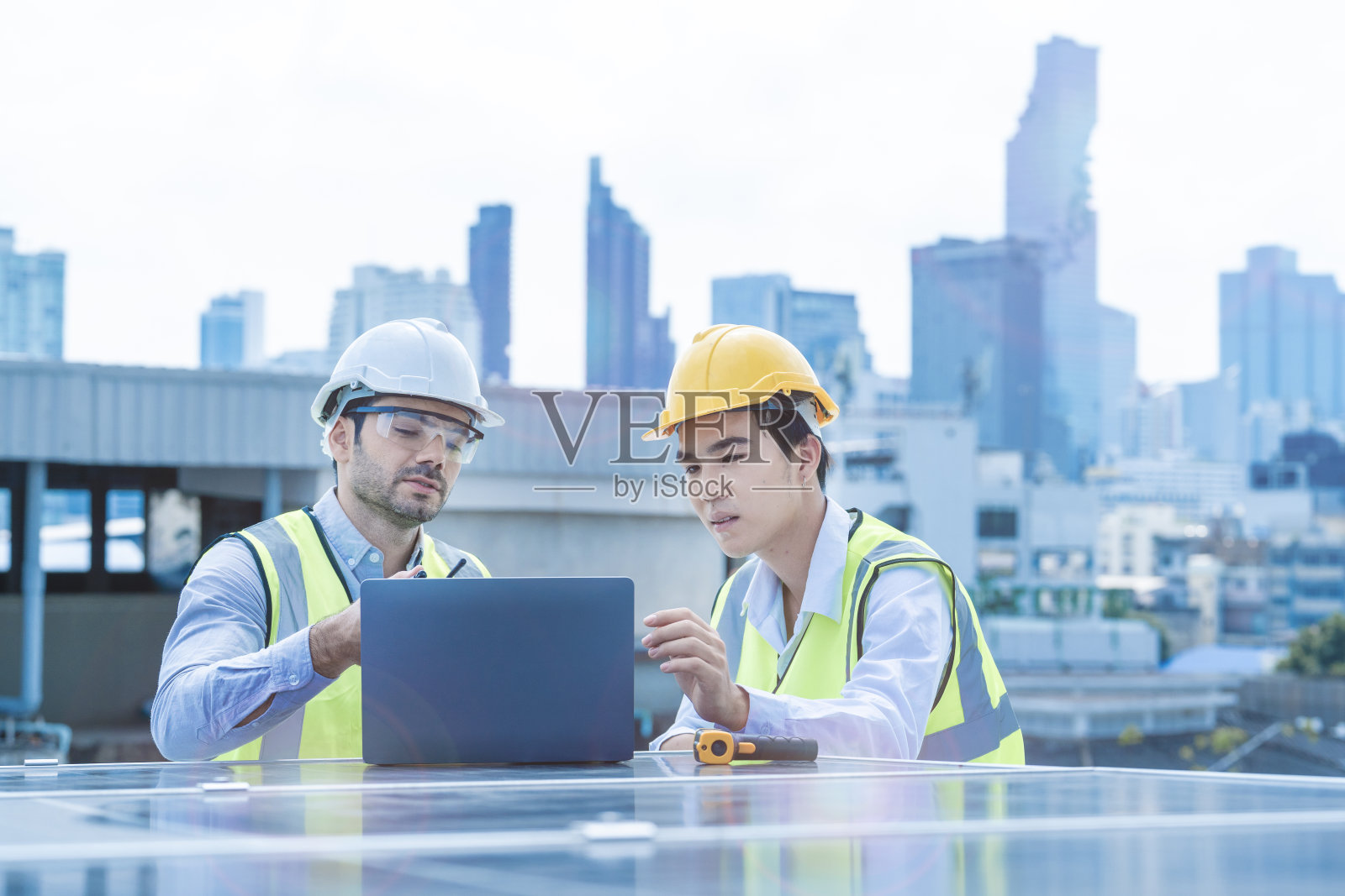 团队工程师通过电子设备检查太阳能电池板或光伏电池的结构。绿色能源工业可再生能源。在塔顶和摩天大楼上工作的工人。照片摄影图片