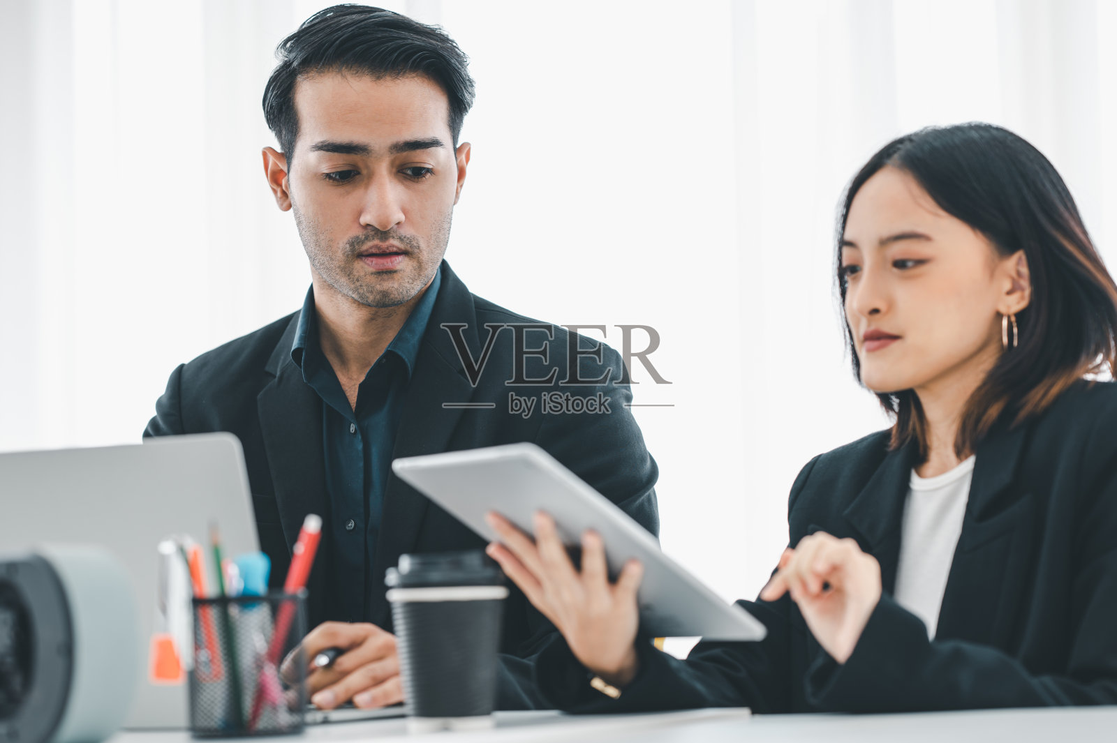 女商人在会议室里与朋友微笑着讨论平板电脑屏幕上显示的图表。头脑风暴和团队合作的概念。照片摄影图片