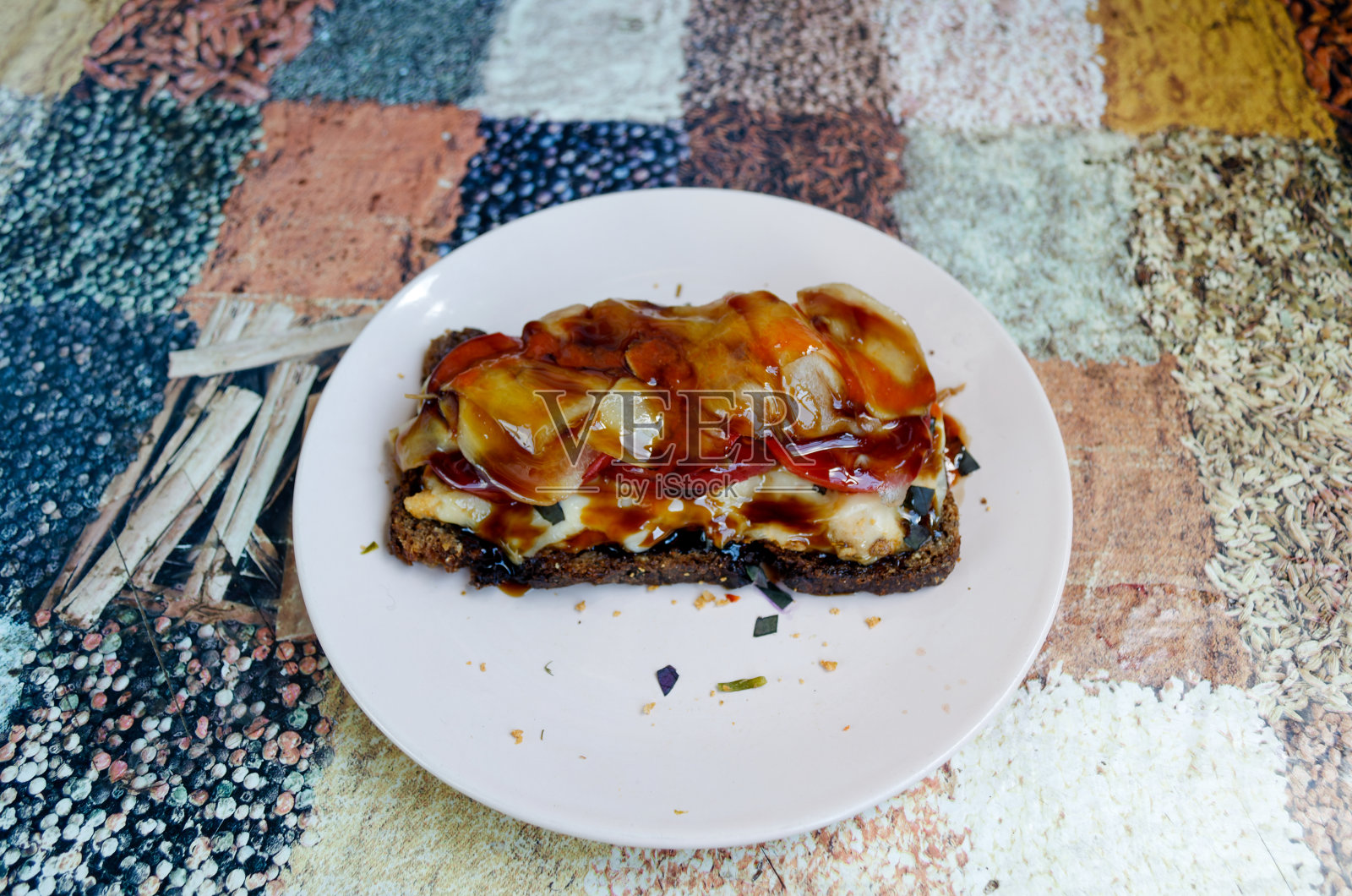 黑麦面包三明治配鳗鱼酱、白姜、西红柿、融化的奶酪、罗勒和鸡肉，放在粉红色的盘子里照片摄影图片