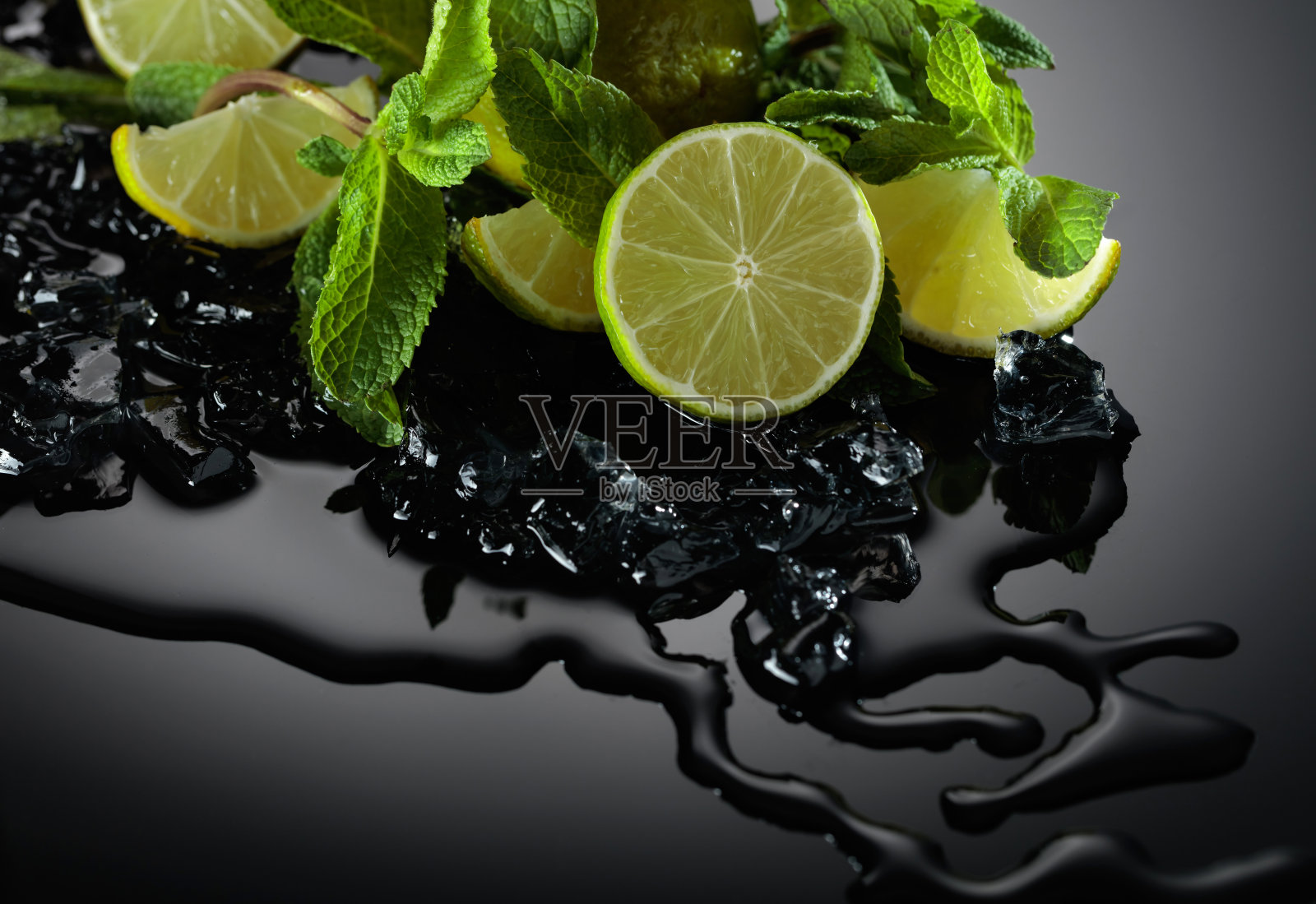 柠檬片、薄荷叶和冰片放在潮湿的黑色背景上。照片摄影图片