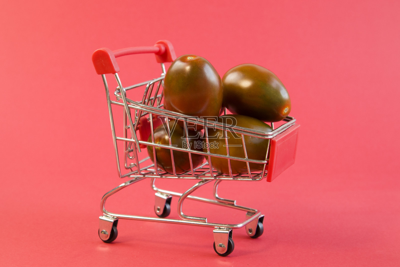 近距离观察小购物车与新鲜的黑色西红柿明亮的红色背景照片摄影图片