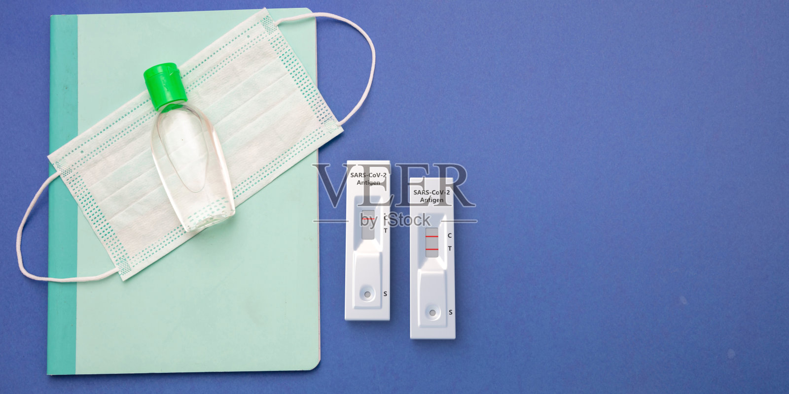 学校的冠状病毒传播预防措施。蓝底快速检测仪、口罩、消毒凝胶、文具照片摄影图片