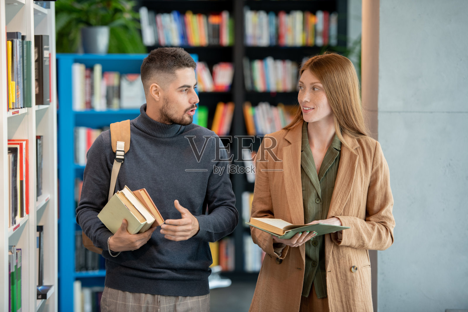 两个学生或同事在图书馆讨论奇书照片摄影图片