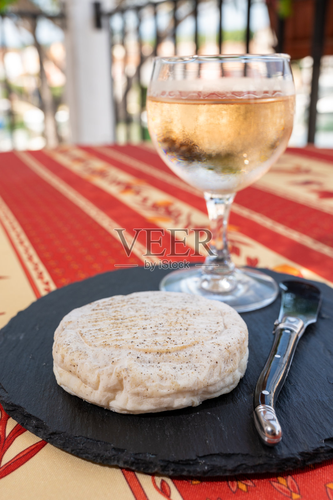 普罗旺斯风味:法国上普罗旺斯阿尔卑斯地区巴侬的小圆奶酪，由山羊奶制成，配以一杯冷玫瑰酒照片摄影图片