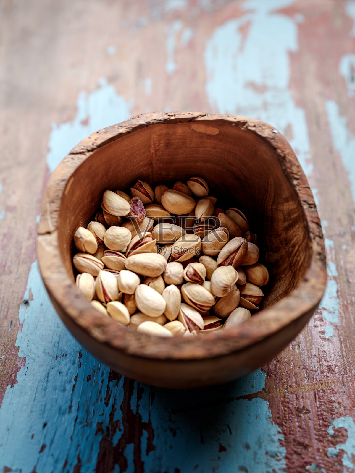 木碗里装着开心果，背景是复古木。堆pistashios。照片摄影图片