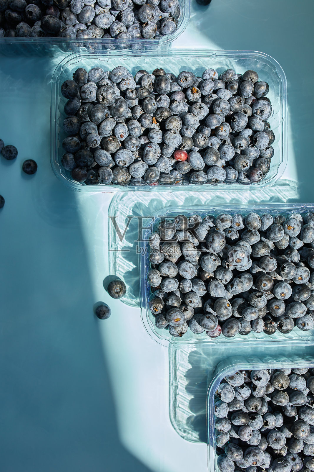 在蓝色背景的碗里放上新鲜多汁的蓝莓照片摄影图片