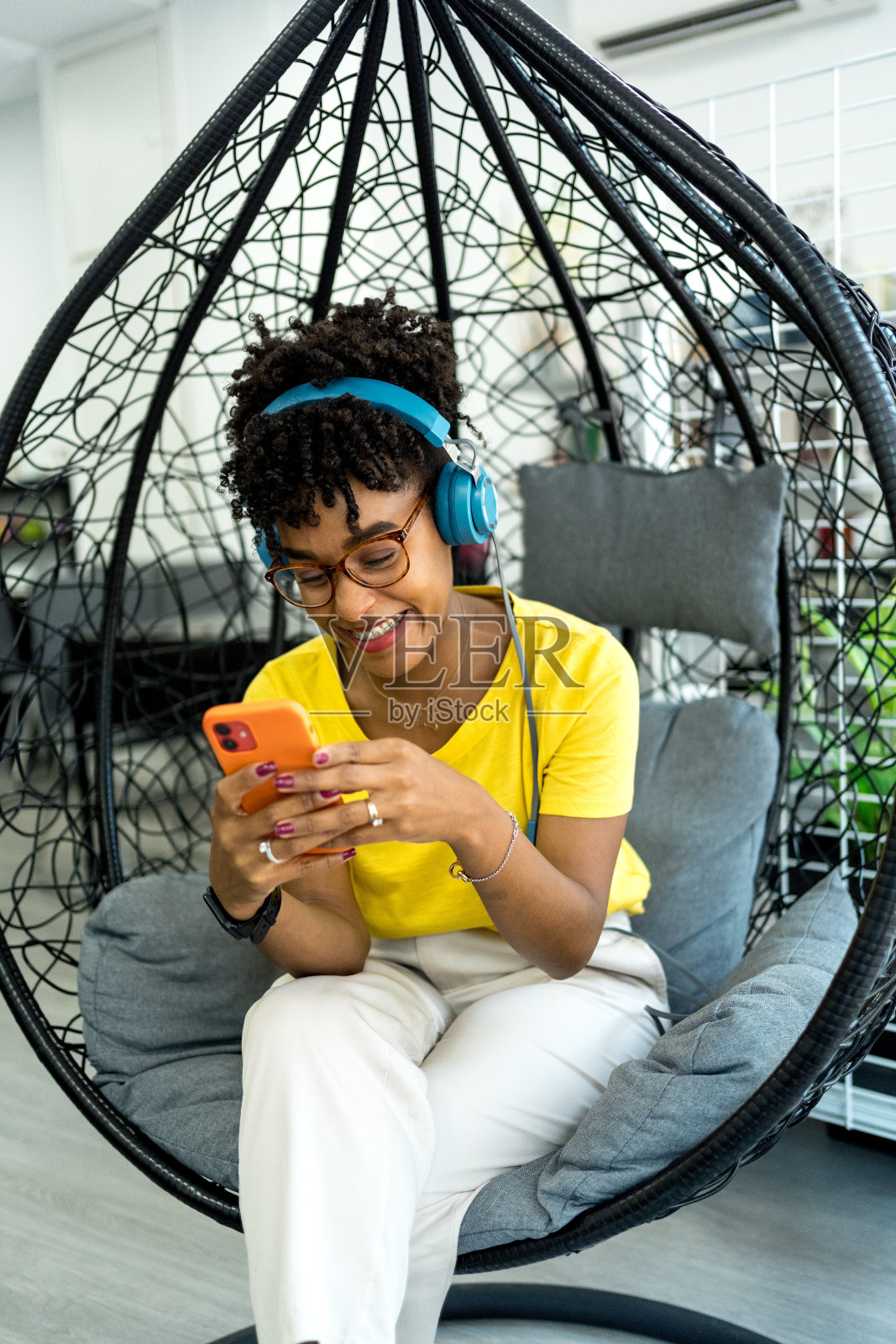 漂亮的非洲裔美国女性在现代办公室里工作，带着笔记本电脑和耳机照片摄影图片