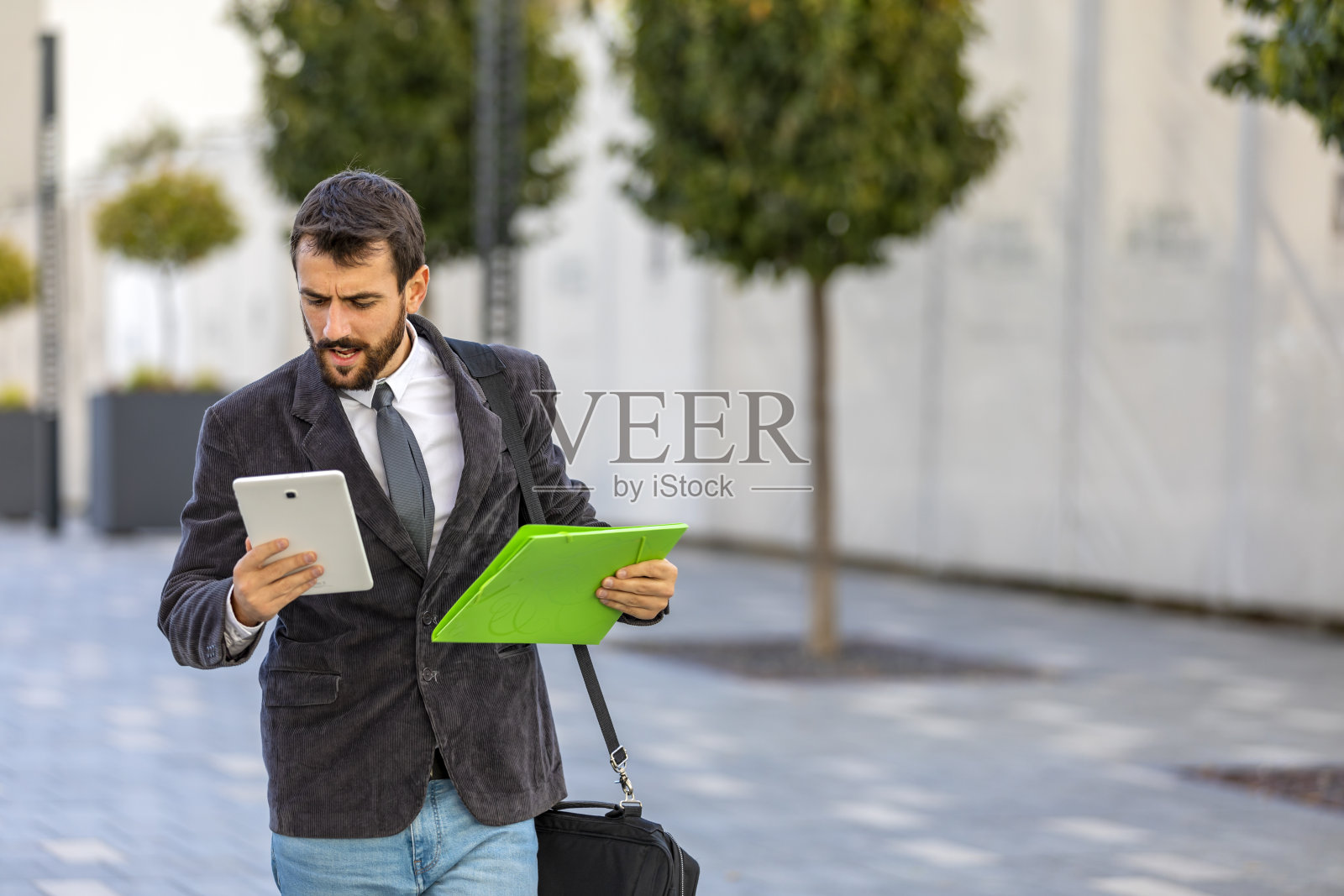 街上的年轻商人一边上班，一边和他的商业伙伴保持联系。照片摄影图片
