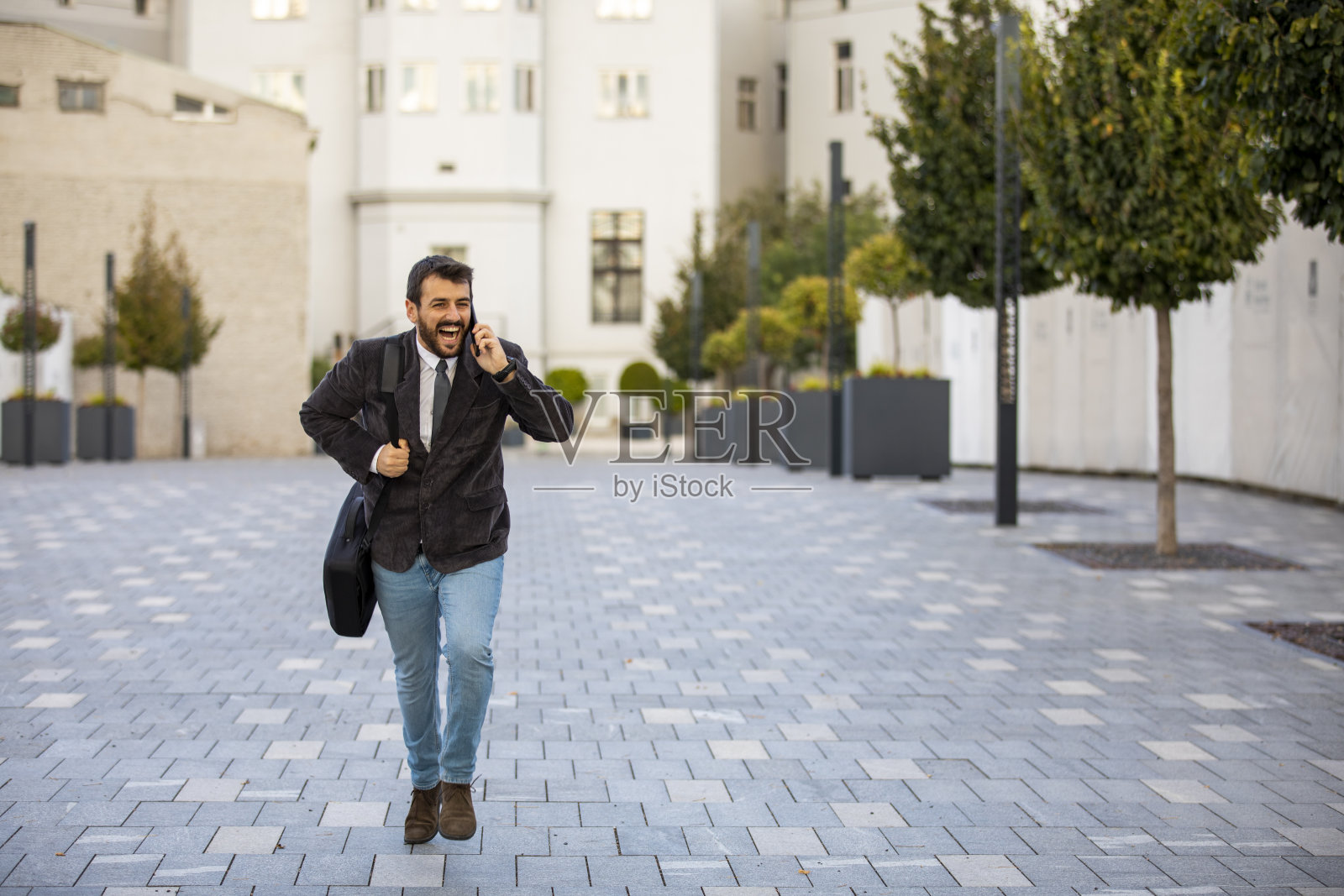 商务人士在市区用手机跑步，急着到达办公室。照片摄影图片