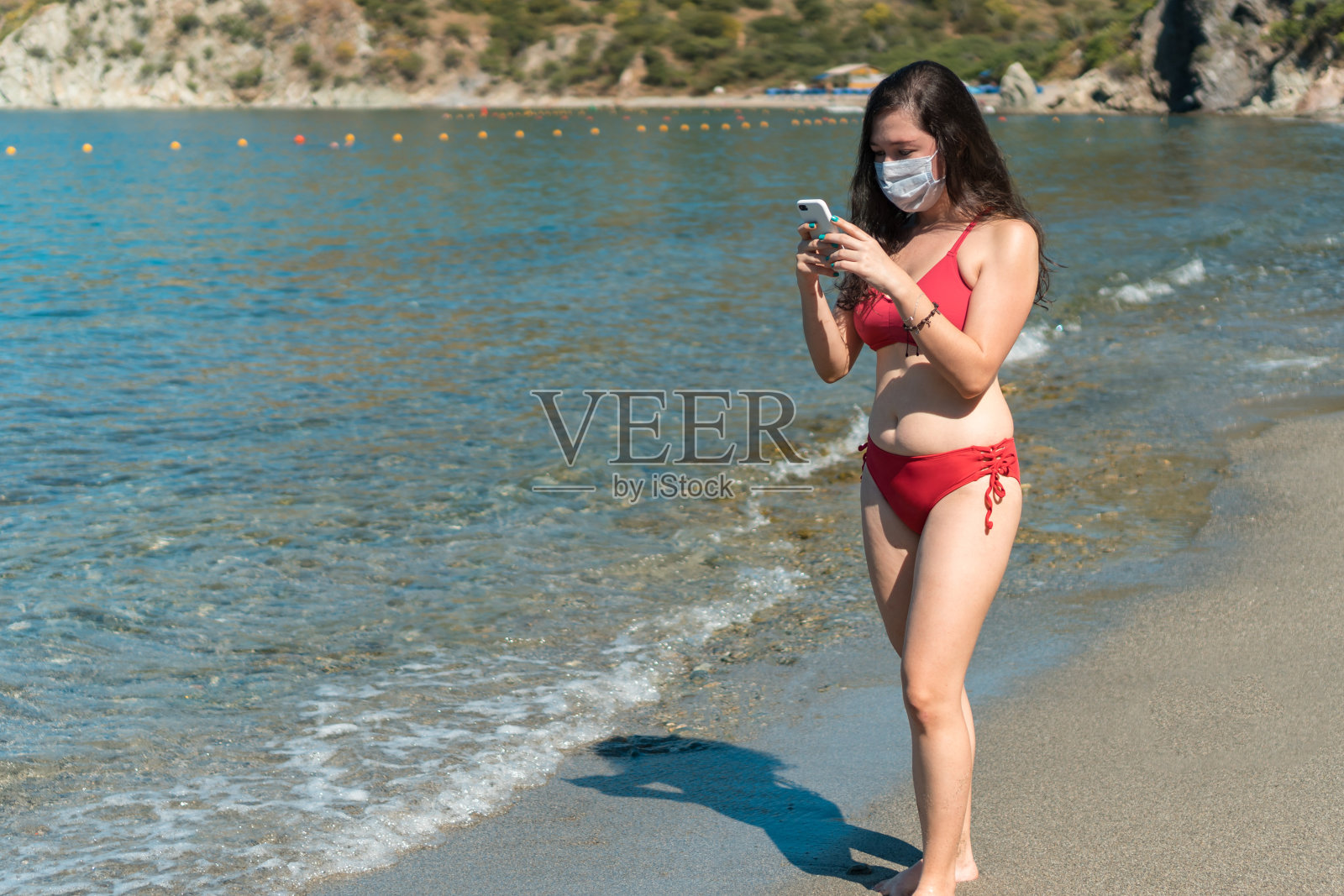 女孩戴着防护口罩，穿着泳衣打电话照片摄影图片