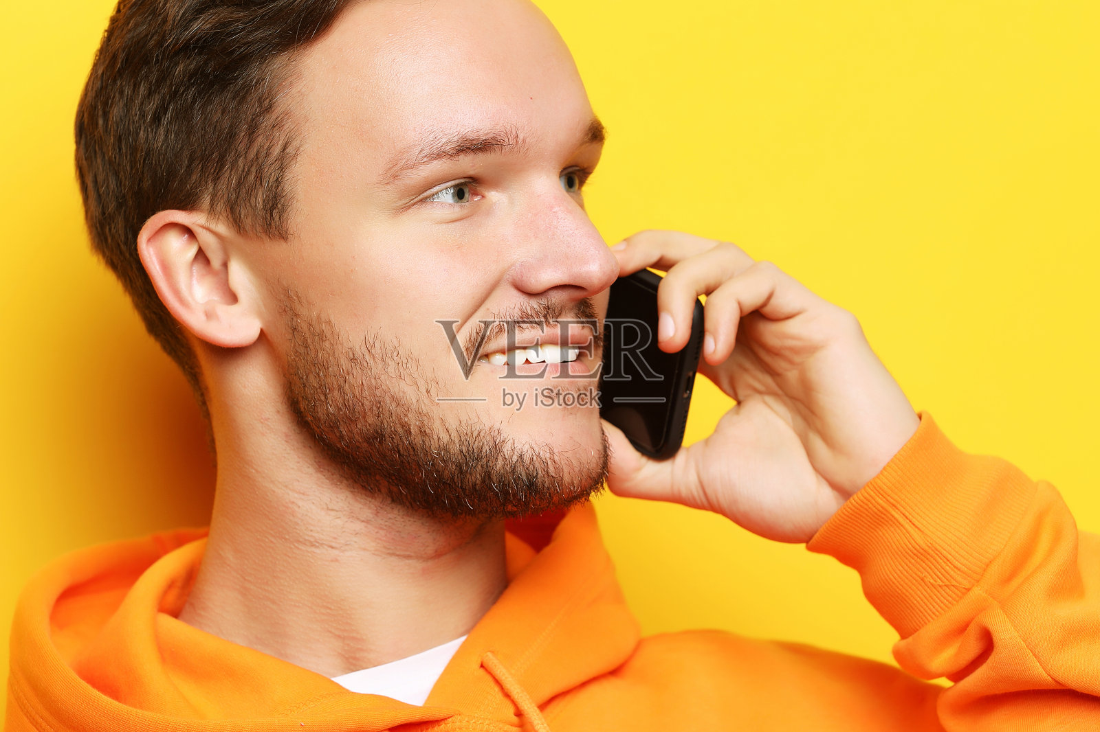 快乐的年轻人在黄色背景下讲手机照片摄影图片