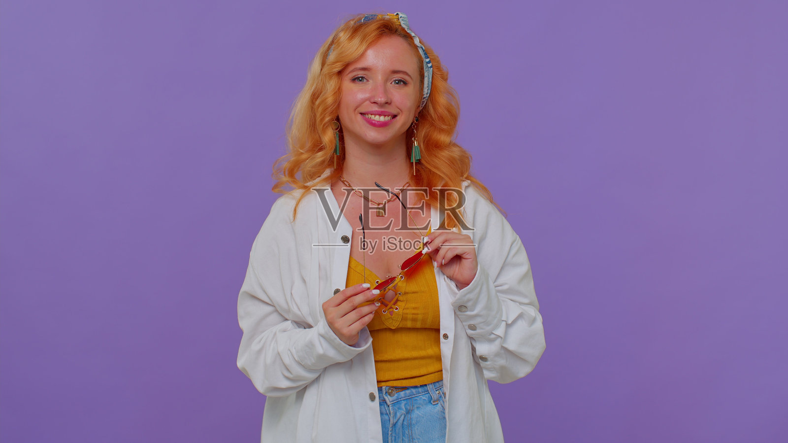 真诚酷开朗时尚的女孩穿着白衬衫戴着墨镜，迷人的笑容挂在紫色的墙上照片摄影图片