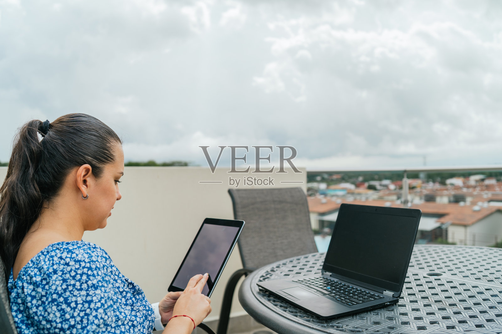 年轻女子坐在阳台上使用笔记本电脑和平板电脑照片摄影图片