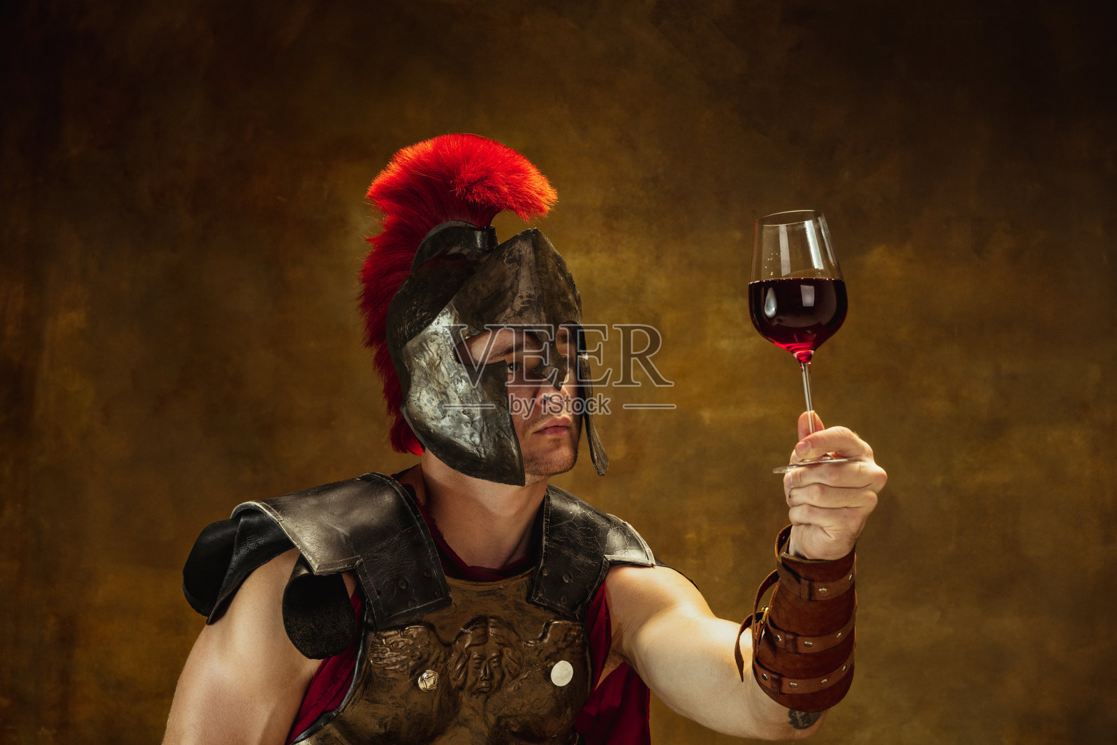 中世纪人的肖像，年轻人，战士或骑士在战争装备孤立在复古的黑暗背景。比较时代，艺术，历史，幽默，复古风格的概念照片摄影图片