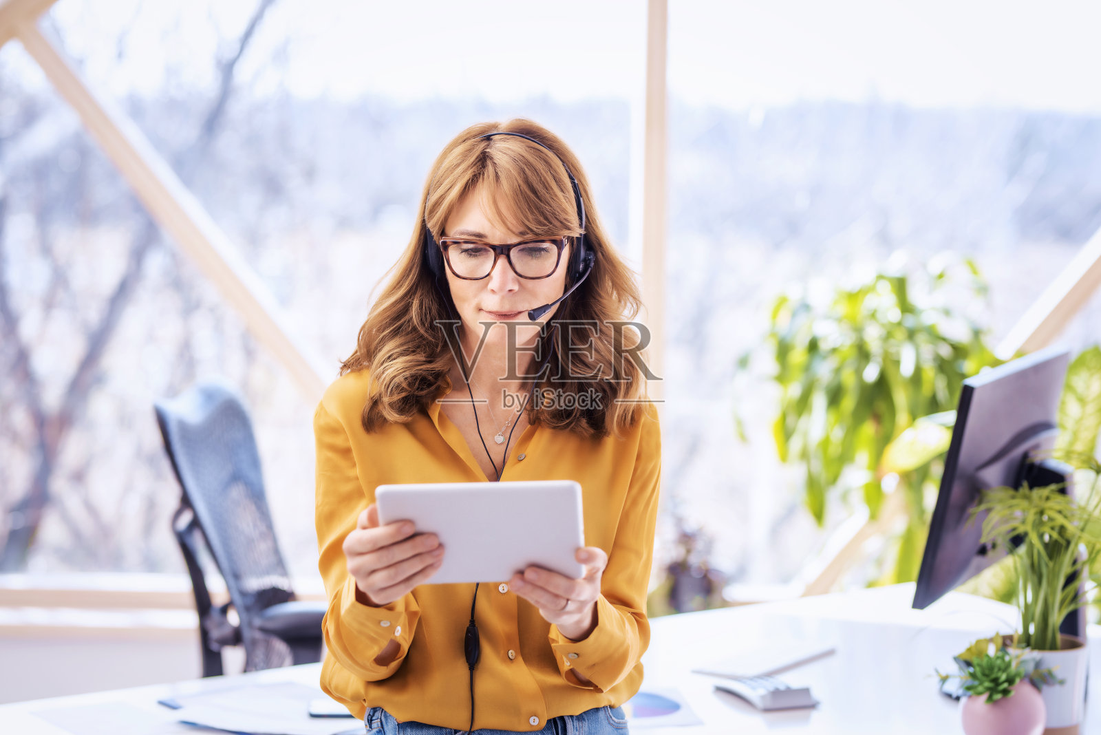 女商人站在桌子前视频通话，手里拿着平板电脑照片摄影图片
