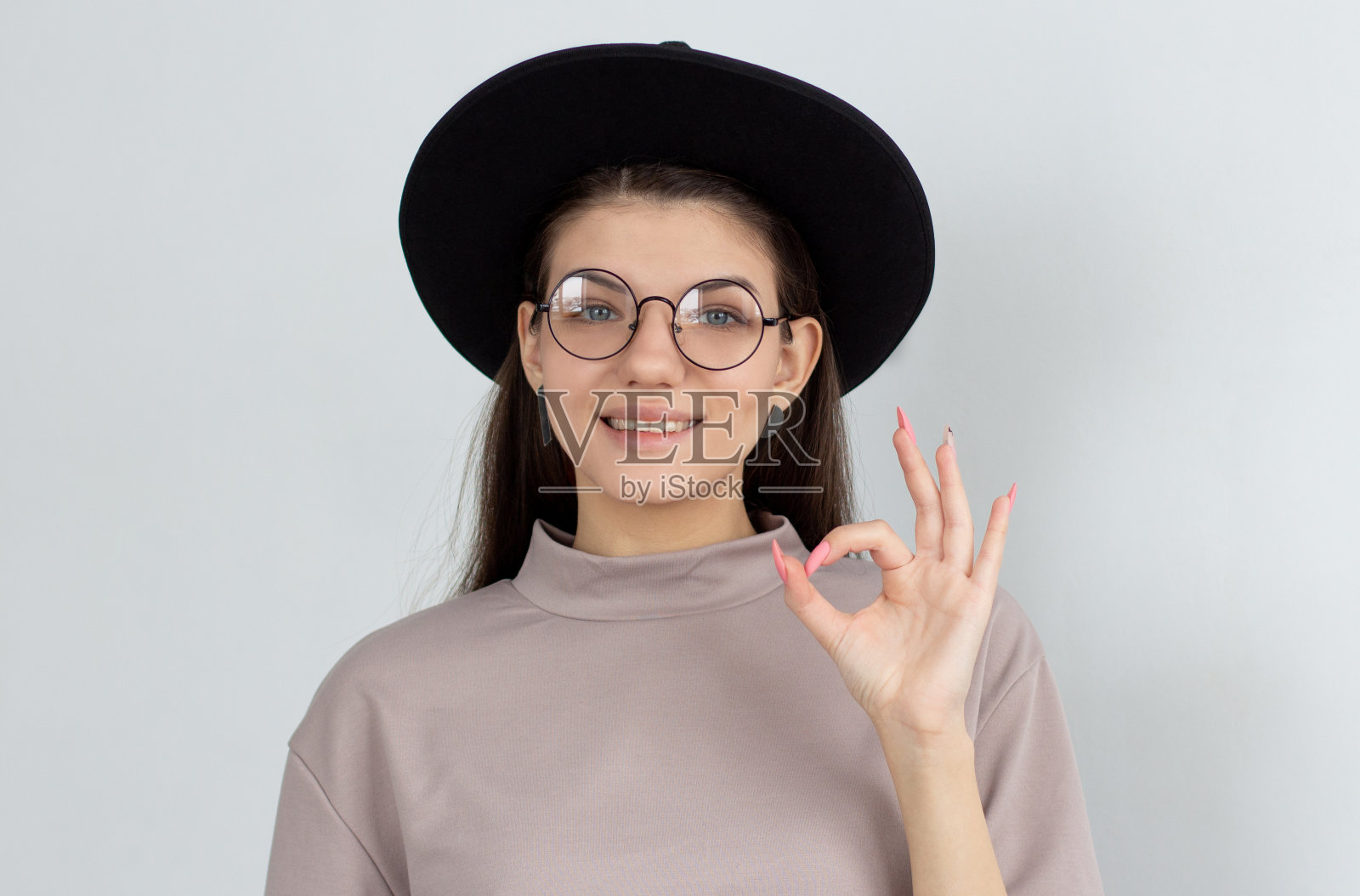 微笑的女人显示ok的标志和看着相机在白色的背景照片摄影图片