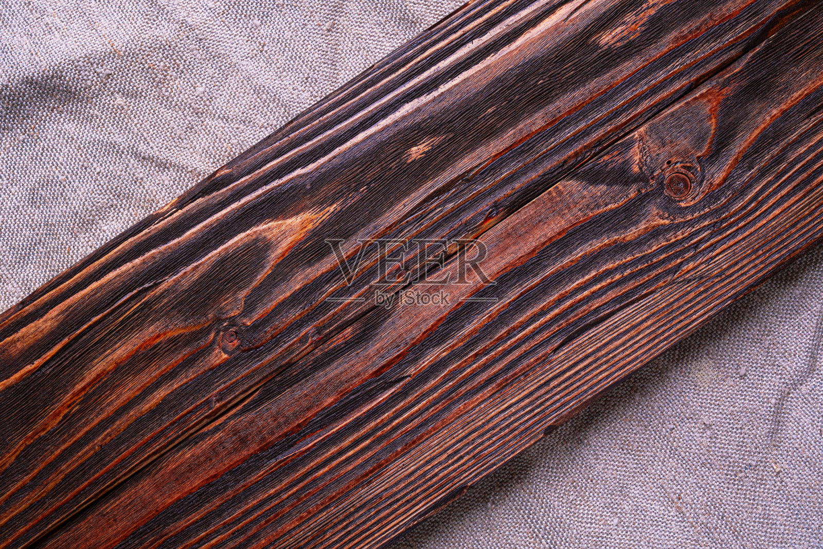 一张深棕色刷过的木板放在灰色粗麻布上，俯视图照片摄影图片