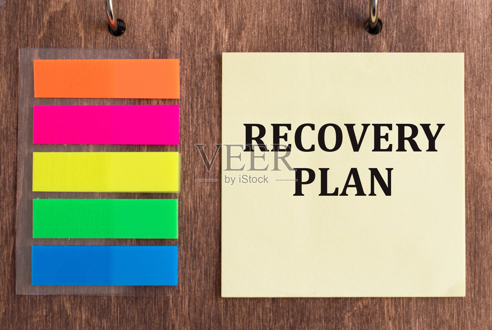 木制背景的黄色便条卡上印有“恢复计划”字样。一个业务概念。照片摄影图片