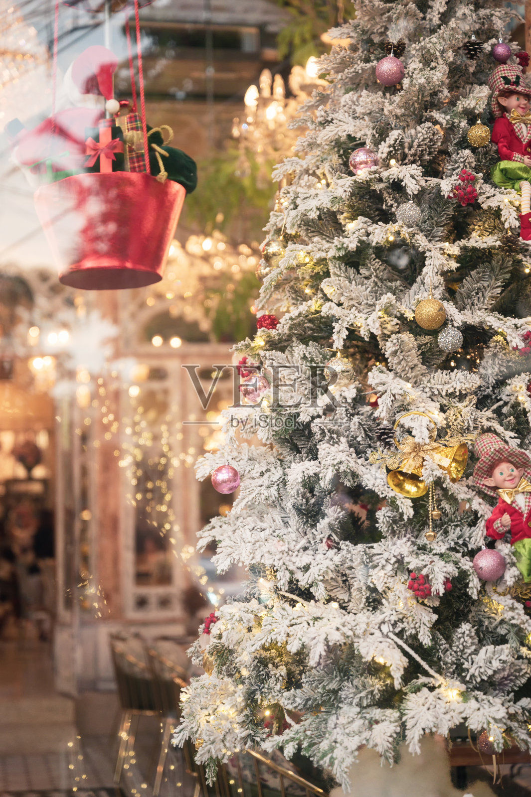 在圣诞节，松树上的雪花与闪闪发光的球和布娃娃装饰照片摄影图片