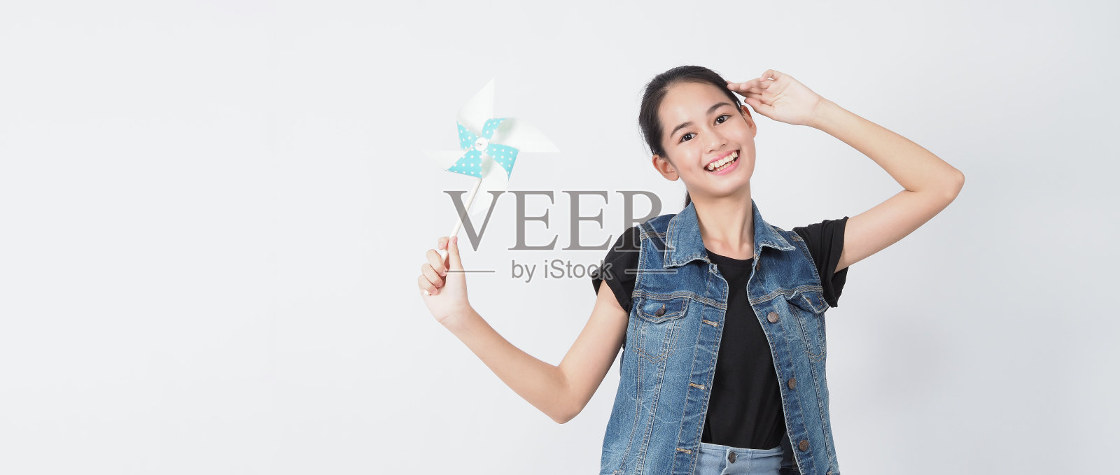 少女和纸风车玩具。肖像少年与蓝色纸风轮木棒手在白色背景摄影棚拍摄。代表风能，这是纯粹的能源和安全的地球。照片摄影图片