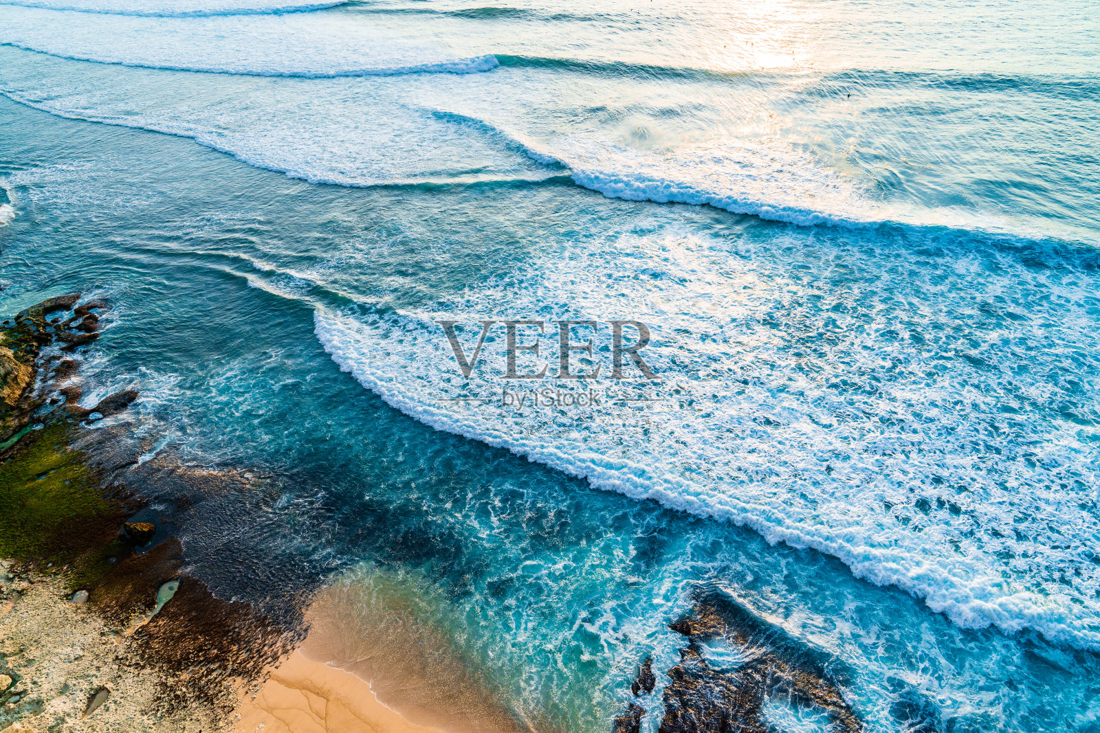 日落时分，海浪拍打着岩石沙滩和悬崖。从以上观点。照片摄影图片