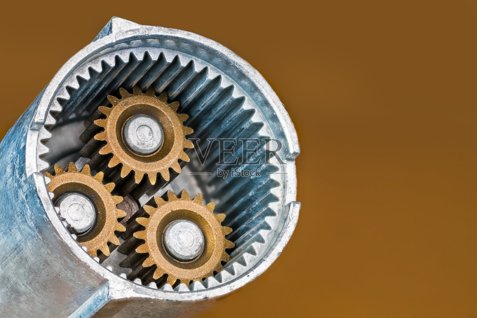 螺旋枪内部部分行星齿轮组的钢齿轮在金棕色背景上照片摄影图片