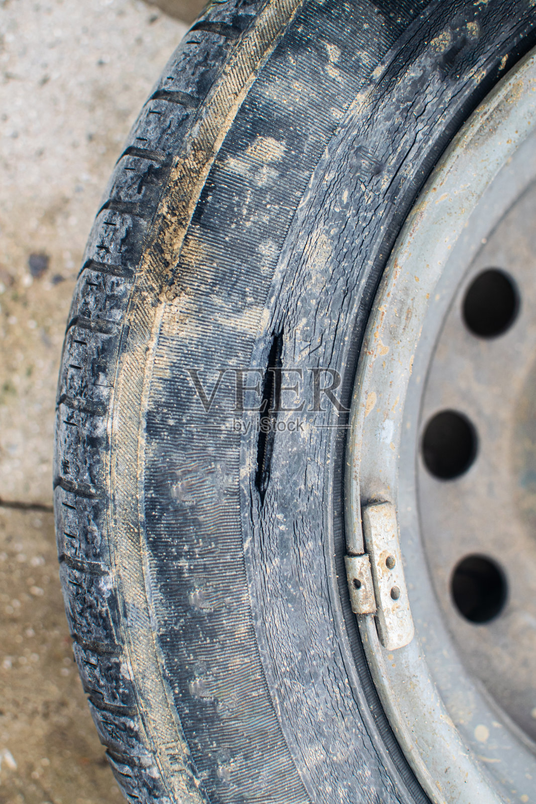 一辆汽车的旧轮胎裂开了。事故风险和不安全轮胎。照片摄影图片