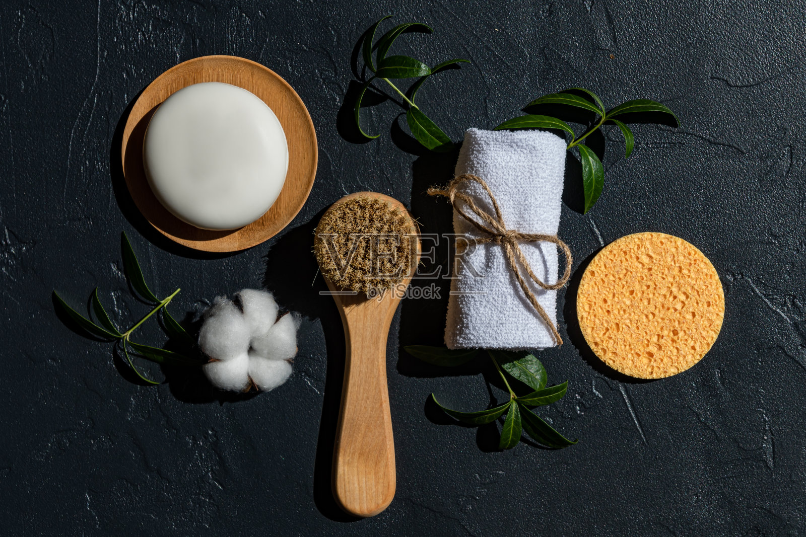 黑色背景的水疗评估。面部按摩刷，棉毛巾，天然海绵和手工有机皂条与草药提取物照片摄影图片