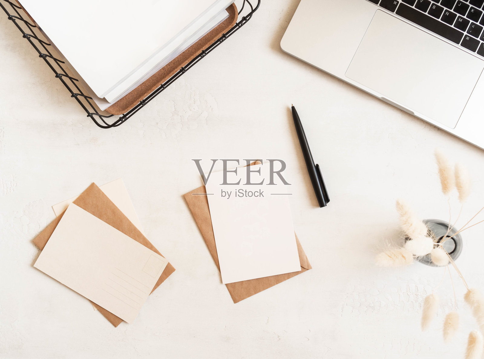 带笔记本电脑、储物篮、鲜花、信封和明信片的家庭办公书桌照片摄影图片