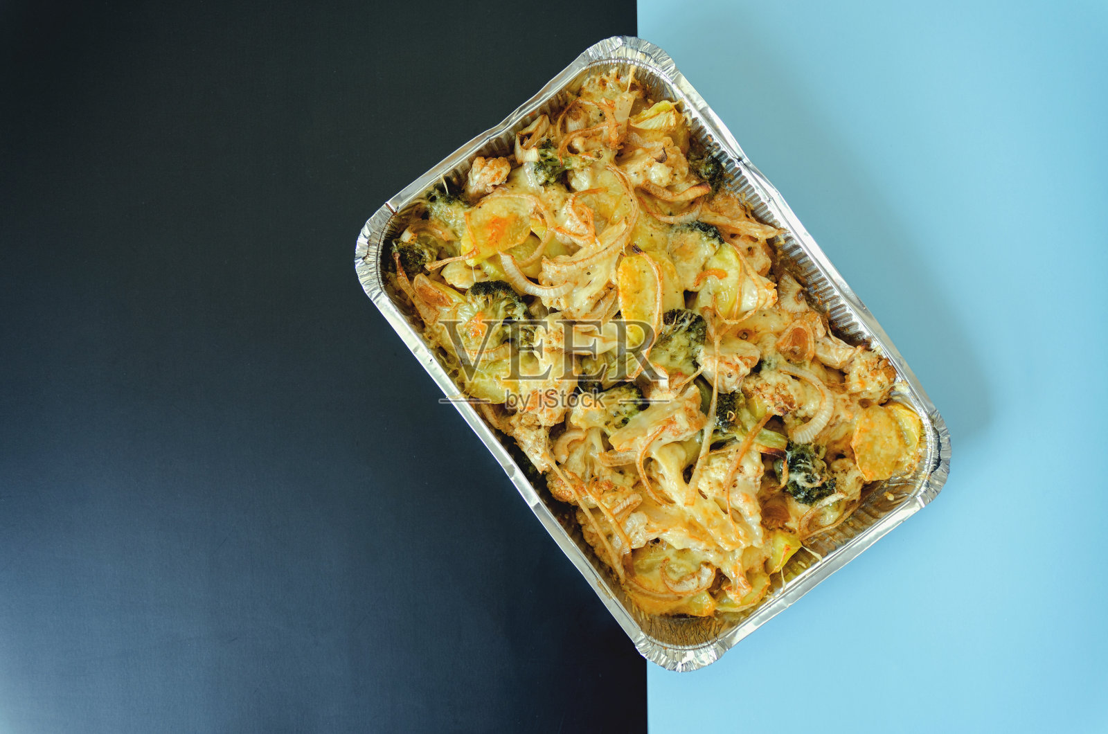 俯瞰素食蔬菜砂锅与土豆，花椰菜，洋葱，花椰菜绿色关闭。烤宽面条。在烤箱里烤土豆。健康的自制素食照片摄影图片