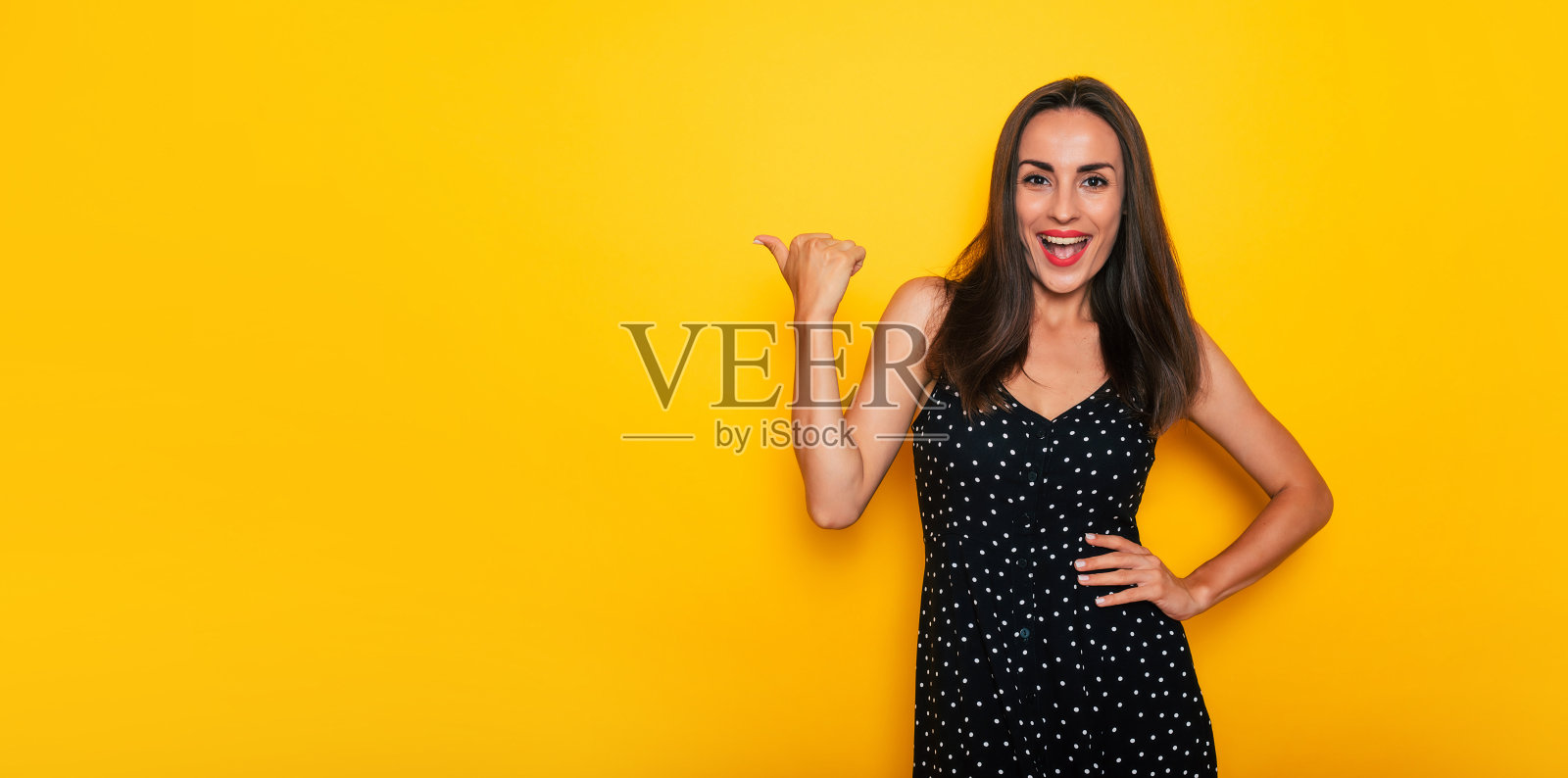 快乐兴奋的美丽微笑黑发女人在黑色的夏装在黄色背景和有乐趣的孤立照片摄影图片