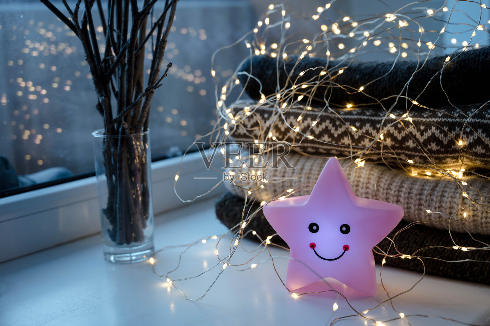 led灯的特写在一堆舒适的针织毛衣上。树枝在玻璃。明星夜灯。Hygge consept。照片摄影图片