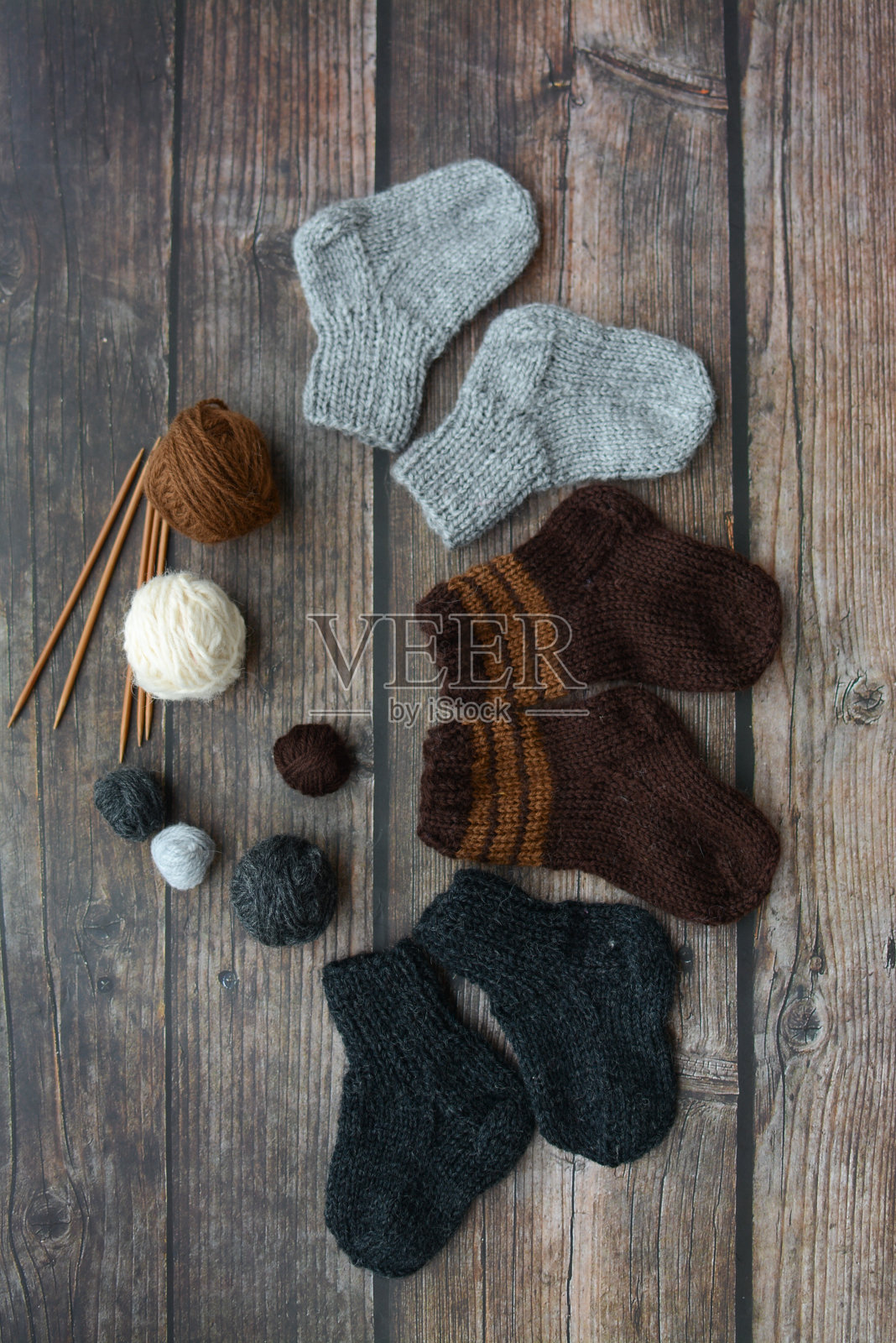 小而温暖的新生袜子由毛线制成，深色木制背景照片摄影图片