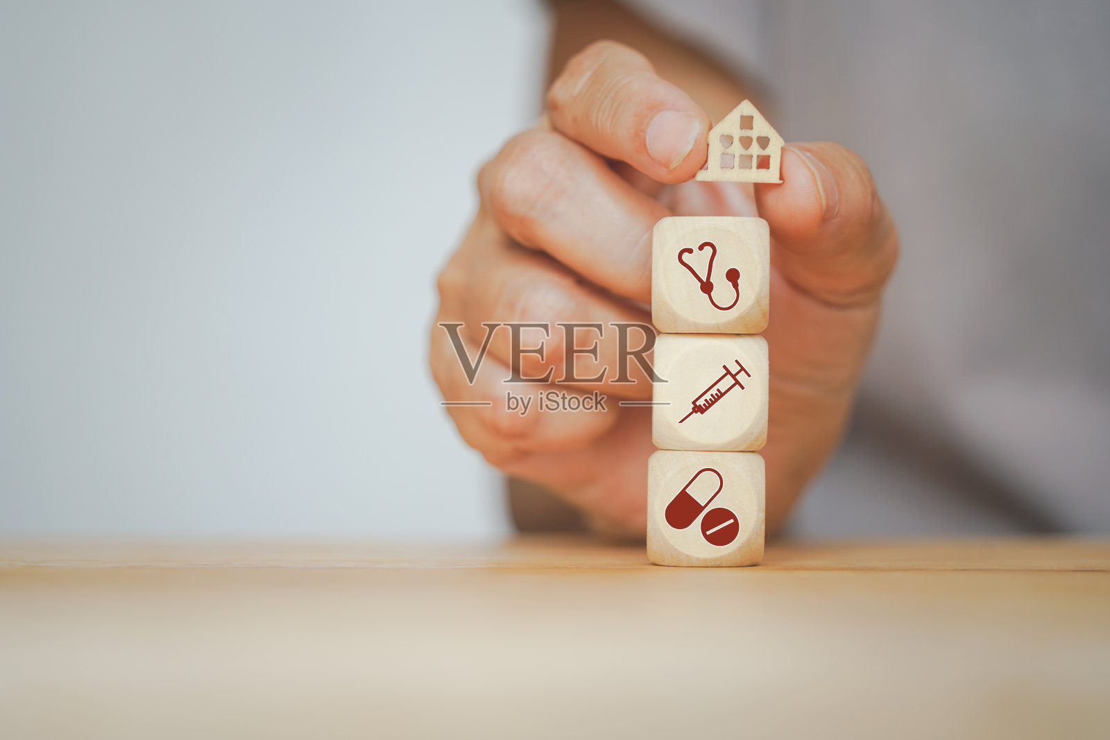 高级人手握迷你木房子和木制立方体上的医疗图标，为年度健康检查，健康和医疗，家庭健康保险，健康，幸福的概念照片摄影图片