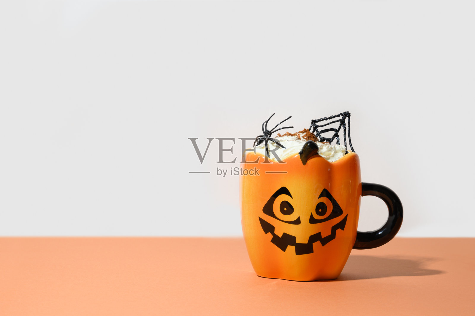 一杯咖啡拿铁装饰蜘蛛网和即将到来的黑蜘蛛。万圣节假期处理。照片摄影图片