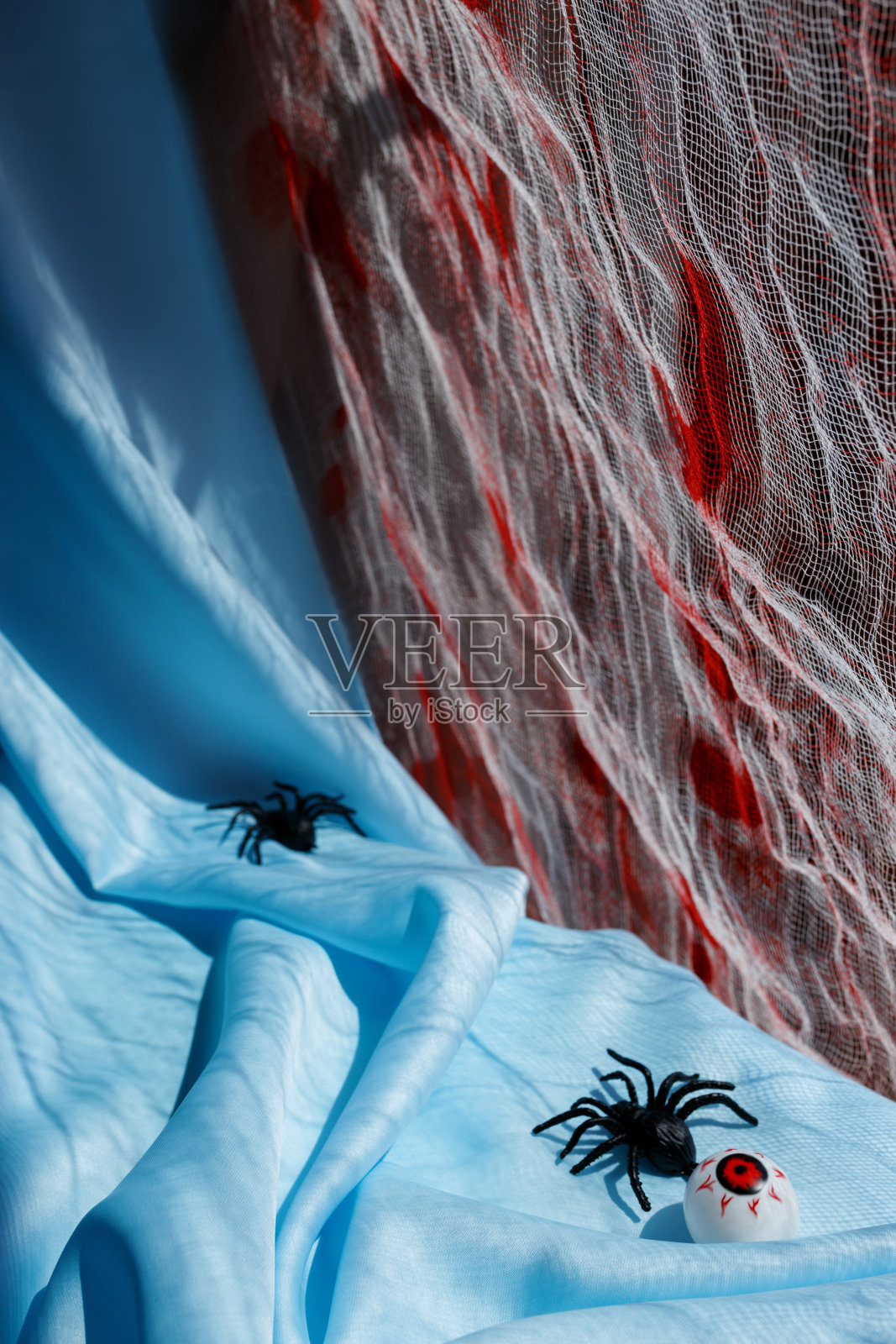 蓝色织物背景上的橙色南瓜，万圣节的象征，坚硬的阴影，蜘蛛照片摄影图片